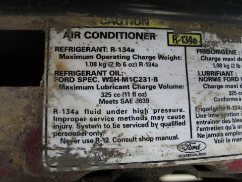 1995 Ford Bronco - A close-up of an air conditioner sticker detailing refrigerant and oil specifications, with a Ford logo at the bottom.