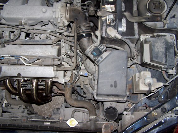 Engine bay with "MAZDA 16-VALVE" on the valve cover and a custom exhaust manifold