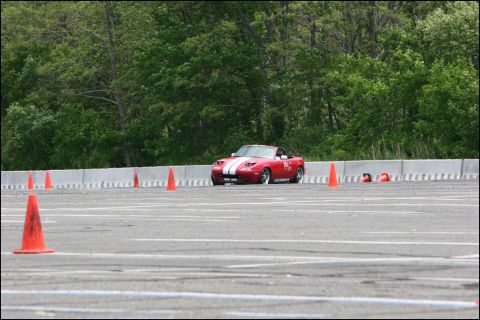 2001 Mercury Grand Marquis - A red convertible sports car navigates a course marked by orange cones on a paved track.