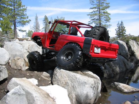 1970 Ford Bronco - This modified 1970 Ford Bronco tackles a challenging rocky terrain with its lifted suspension and off-road tires.