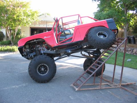 1970 Ford Bronco - Modified 1970 Ford Bronco with extensive roll cage and off-road tires is shown climbing a ramp.