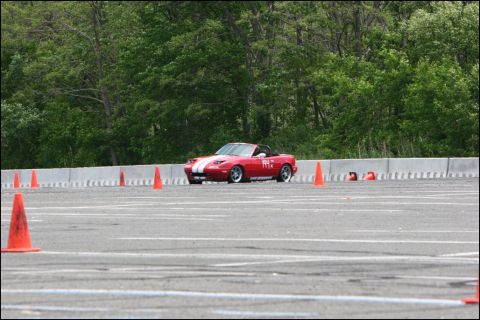 2001 Mercury Grand Marquis - A red convertible sports car navigates an autocross course marked by orange cones.