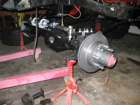 1970 Ford Bronco - Close-up of vehicle suspension and brake components being worked on in a garage.