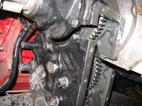 1970 Ford Bronco - Detail of engine components, including gears and bolted metal plates, with a red background element.