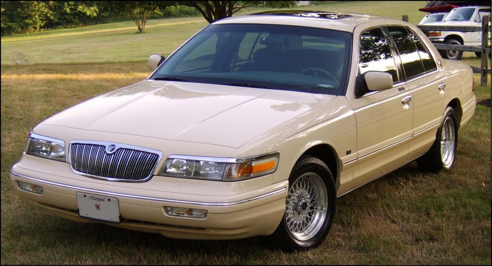 Cream Mercury Grand Marquis sedan, front 3/4 view, parked on grass