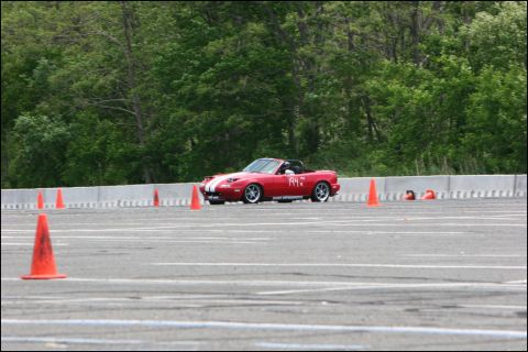 2001 Mercury Grand Marquis - Red Mazda Miata convertible with racing stripes navigates a course marked by orange cones.