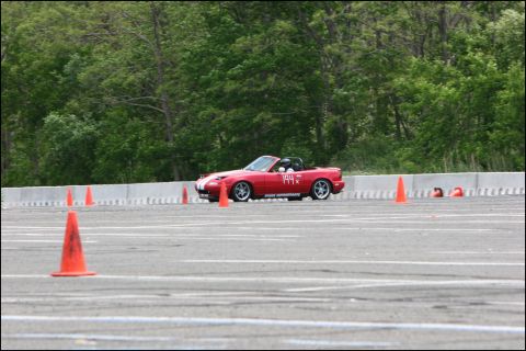 2001 Mercury Grand Marquis - A red convertible navigates an autocross course, marked by orange cones, with trees in the background.