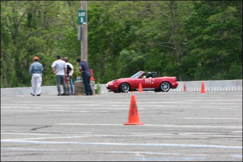 2001 Mercury Grand Marquis - A red convertible sports car navigates an autocross course marked by orange cones.