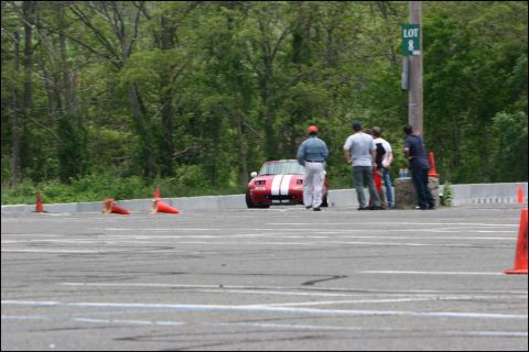 2001 Mercury Grand Marquis - A red sports car with white stripes is on an autocross course with people watching.