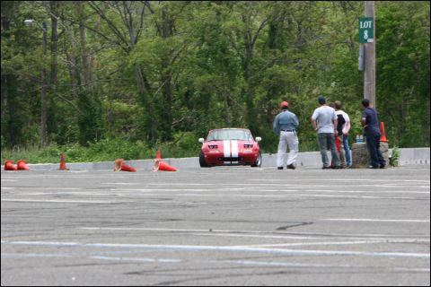2001 Mercury Grand Marquis - A red sports car with white racing stripes is parked on a track, with several people observing nearby.
