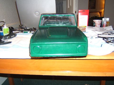 1988 Ford Bronco - A green toy truck body sits on a wooden table, surrounded by crafting supplies.