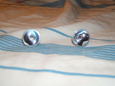 1988 Ford Bronco - Two chrome lug nuts are displayed on a striped cloth background.
