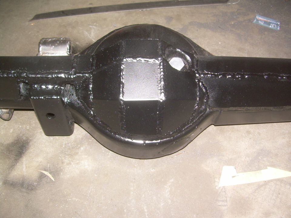 Black painted rear axle housing with visible welds and a square patch on the differential cover