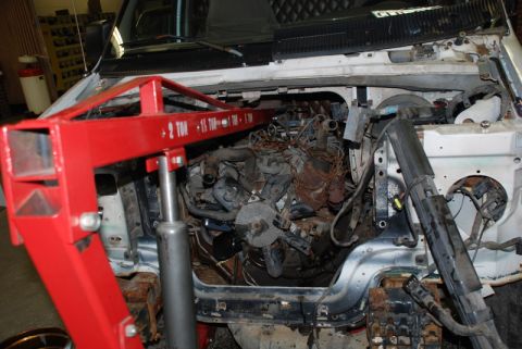 1996 Ford Bronco - Engine bay of a van with engine hoist positioned over the empty space.