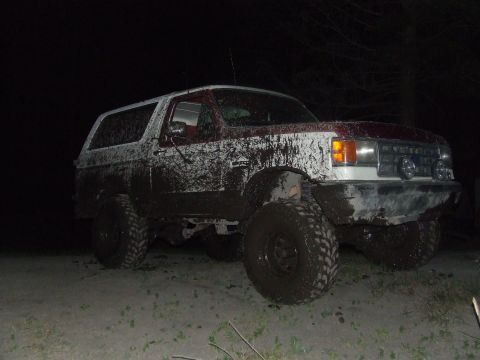 1990 Ford Bronco - This heavily mud-splattered SUV is viewed from the front-right at night.