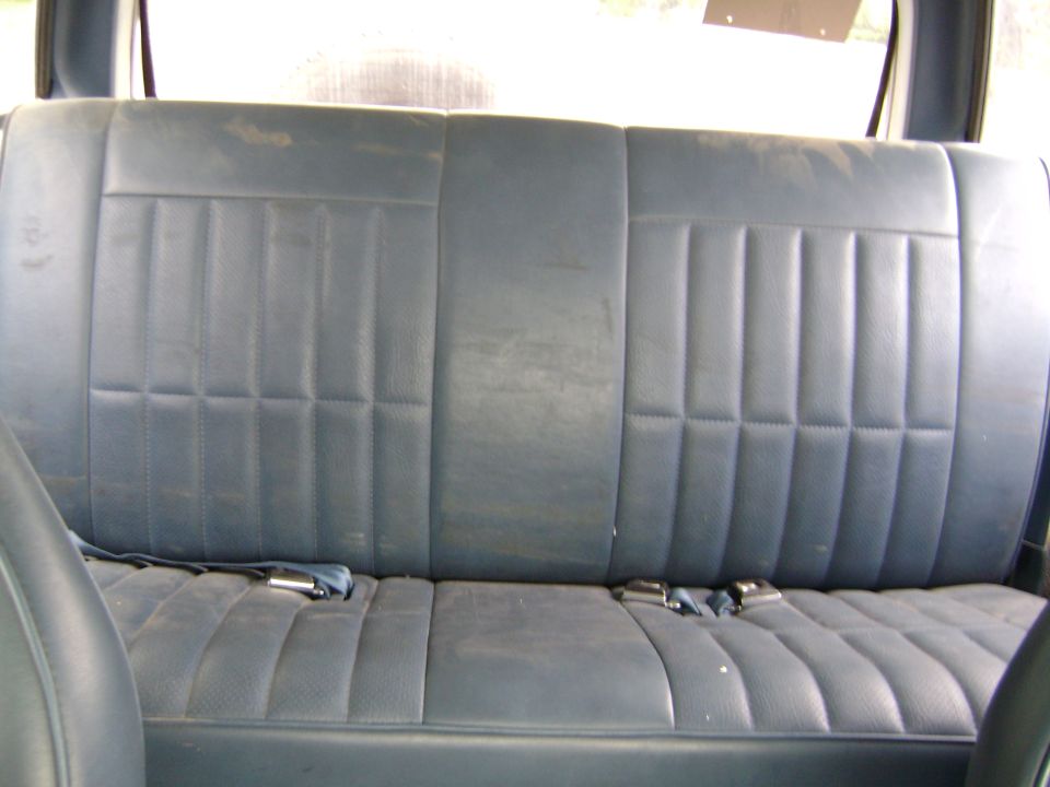 Worn dark blue rear bench seat inside a vehicle