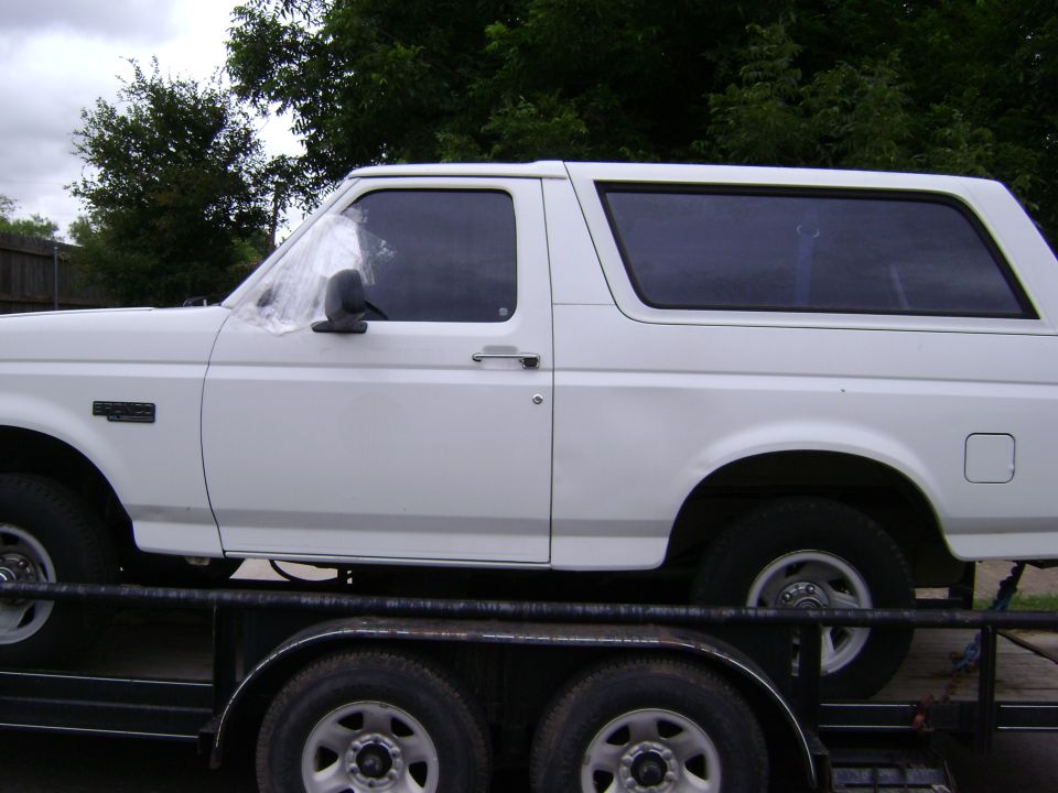 Side profile of a white Ford Bronco on a tandem-axle trailer