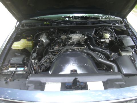 1996 Ford Crown Victoria - The engine bay of a vehicle is shown with the hood open. Text on the fan shroud reads "CAUTION FAN".