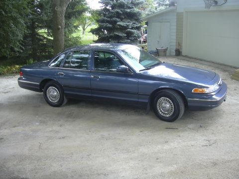 1996 Ford Crown Victoria - Blue 1996 Ford Crown Victoria sits on a dirt driveway next to a garage.