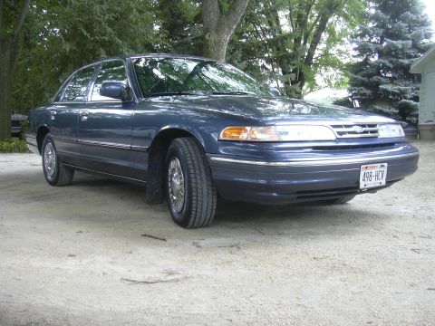 1996 Ford Crown Victoria - The front quarter view of a dark blue sedan shows its grille, headlights, and front bumper with a license plate.