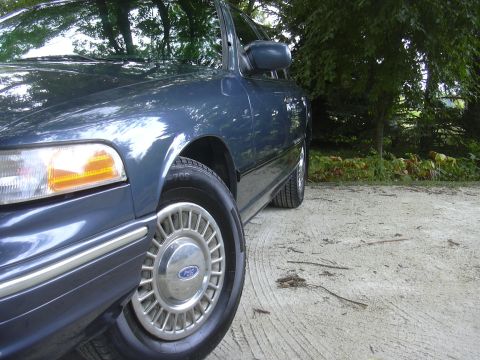 1996 Ford Crown Victoria - The front passenger side of a blue 1996 Ford Crown Victoria is visible, parked outdoors.