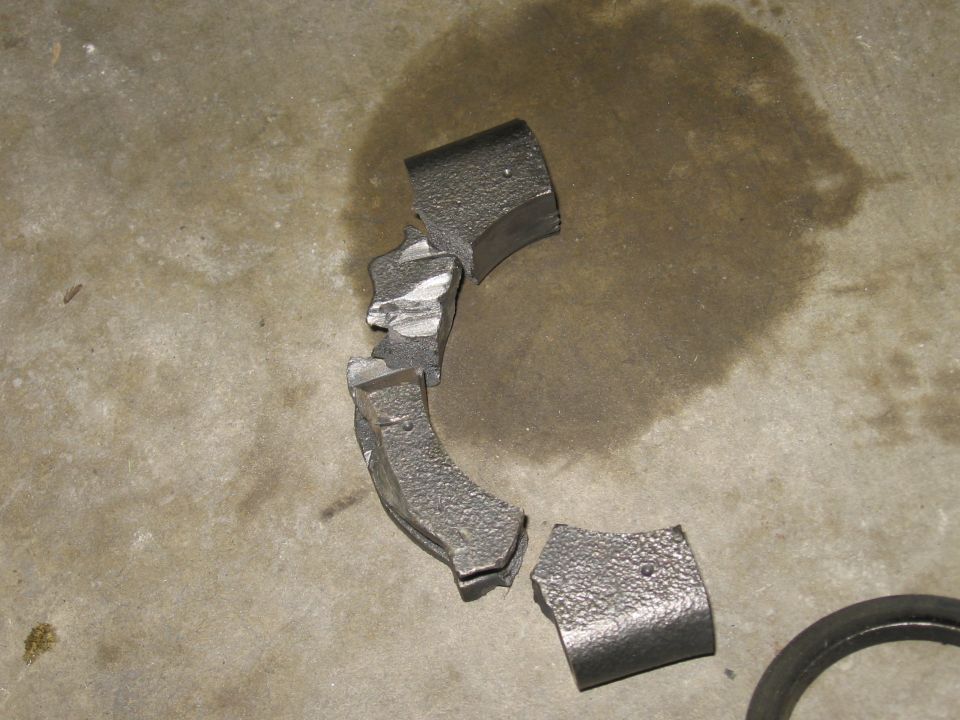 Broken metal part on concrete floor, with a water stain and a SuperMotors logo