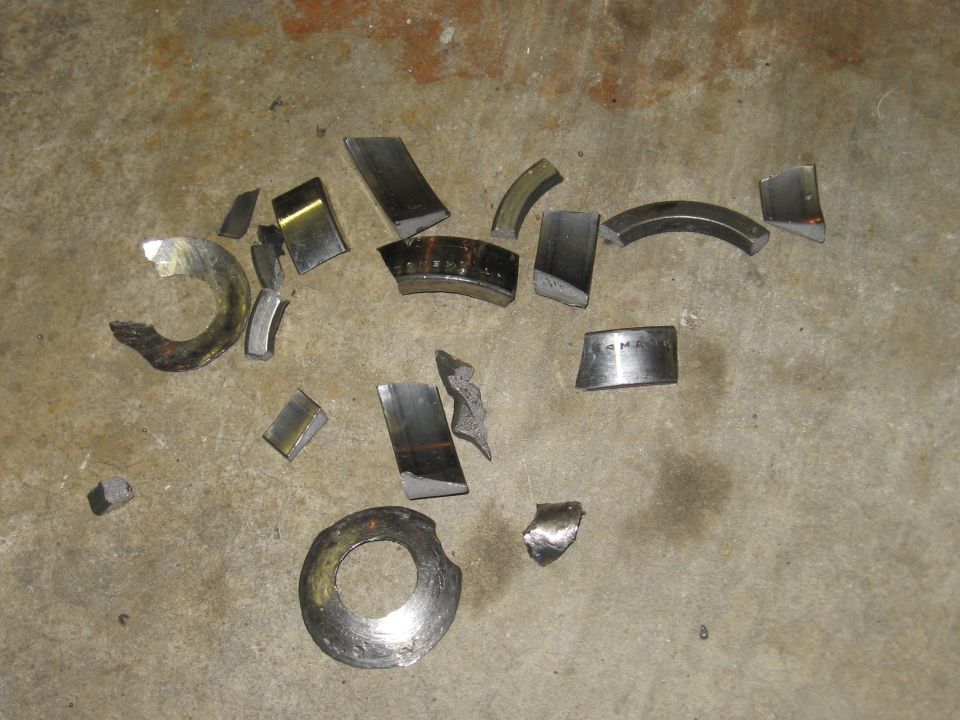 Scattered pieces of broken engine bearing shells on a concrete floor