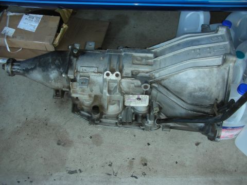 1998 Ford Crown Victoria - Automatic transmission removed from a vehicle, resting on a concrete floor.