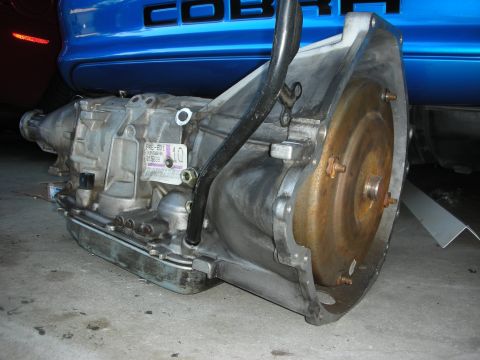 1998 Ford Crown Victoria - Automatic transmission with visible part number PKE-201. A blue car with COBRA lettering is in the background.