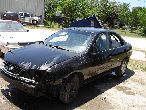 Black sedan with front end damage, parked outside next to a white car