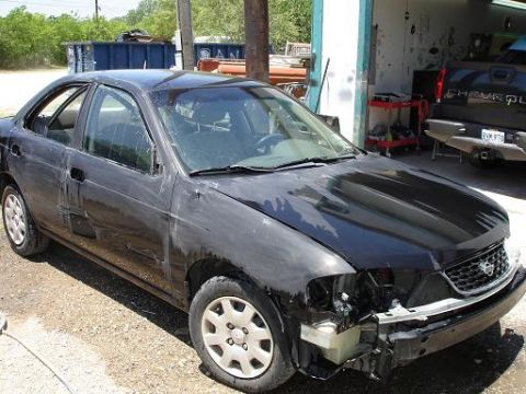 1996 Ford F-150 - A black sedan is parked outside a garage with a Chevrolet truck visible in the background.