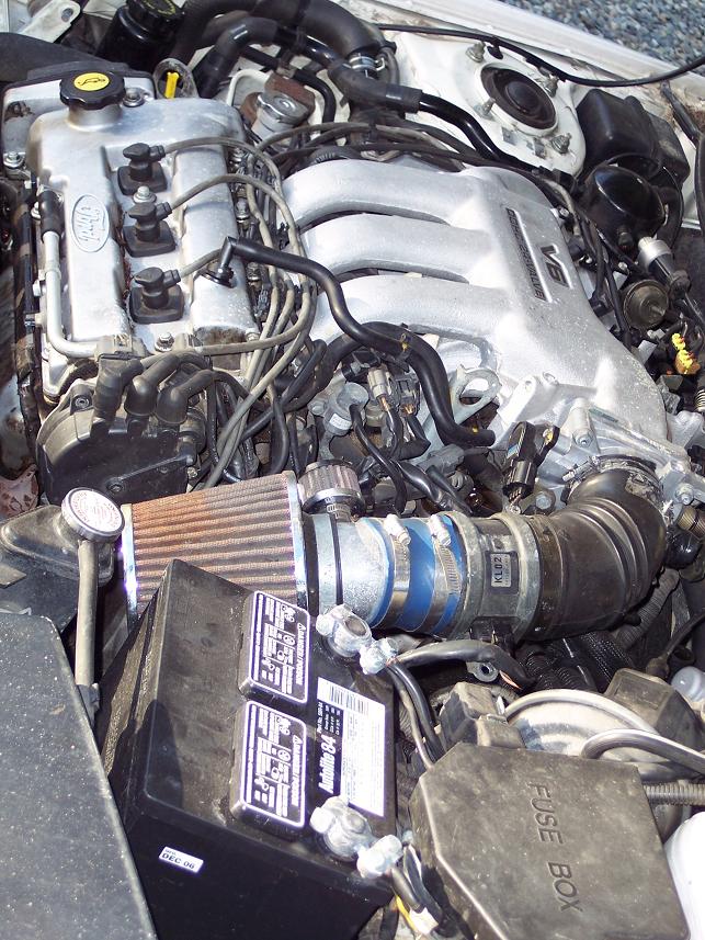Engine bay V6 intake manifold, aftermarket air filter, and battery