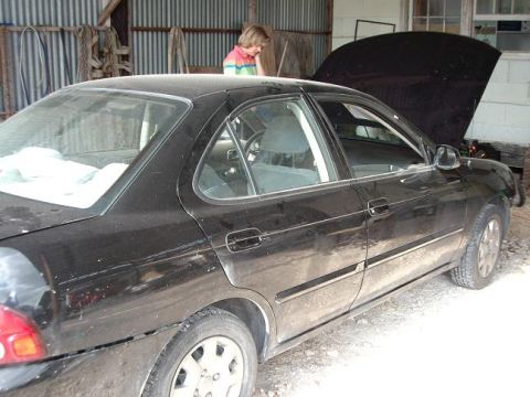 1996 Ford F-150 - A black sedan sits in a garage with its hood open, and a person stands in the background.