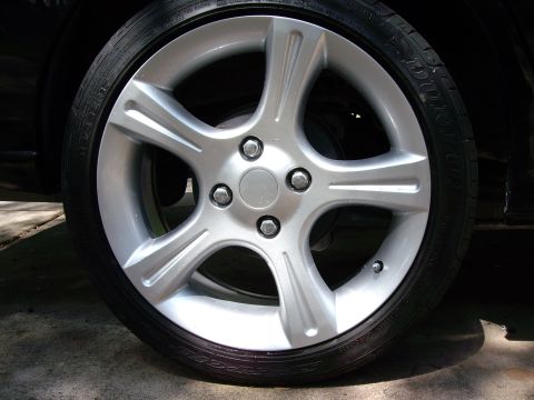 1996 Ford F-150 - A close-up view of a car's wheel and tire assembly, showing the silver alloy rim and black tire tread.