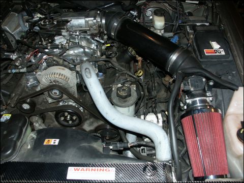 2001 Mercury Grand Marquis - Engine bay a custom black air intake system with a prominent red air filter and various hoses and engine components.