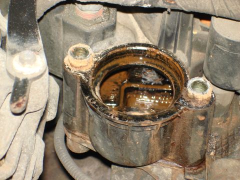 1998 Ford Crown Victoria - This is a close-up view of an engine part, likely a thermostat housing, filled with murky, rusty fluid.