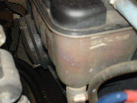 1998 Ford Crown Victoria - Close-up of a vehicle's coolant reservoir, showing fluid level markers.
