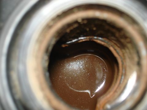 1998 Ford Crown Victoria - Engine oil with sediment visible inside a metal container.