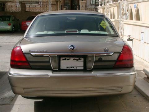 2007 Mercury Grand Marquis - Straight-on rear view of a champagne gold Mercury Grand Marquis sedan parked in a walled driveway, showing the "GRAND MARQUIS GS" trunk bad…