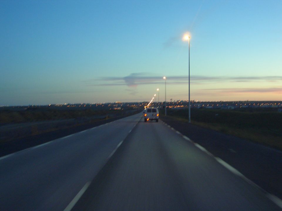 Van driving on a highway at dusk with city lights in the distance