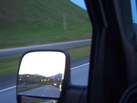 1974 Ford Bronco - View from a vehicle's side mirror captures a scenic landscape with distant lights and mountains.