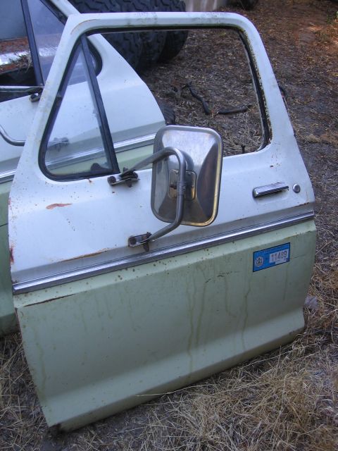 1989 Ford Bronco - A detached truck door with a side mirror is shown, a blue sticker with a number on it.