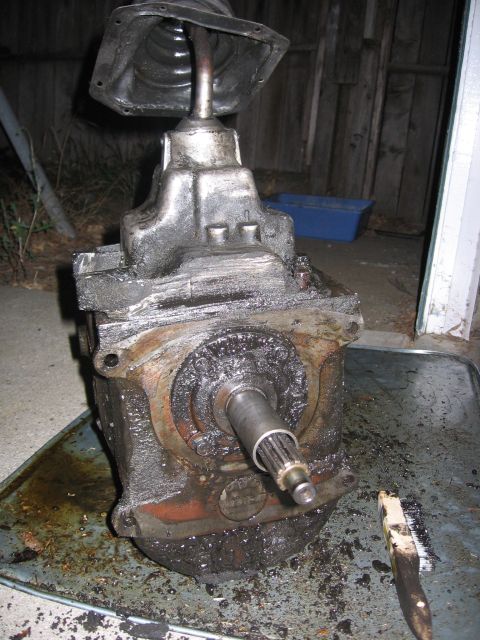 1989 Ford Bronco - A dirty transmission sits in a tray with a brush nearby, suggesting it is being cleaned or worked on.