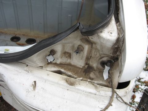 1992 Ford Crown Victoria - The interior of a vehicle's trunk reveals exposed metal, wiring, and a rubber seal, suggesting damage or repair.