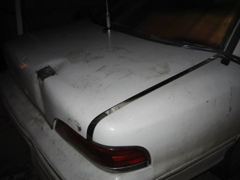 1992 Ford Crown Victoria - The rear of a white sedan shows extensive damage to the trunk area, indicating a collision.