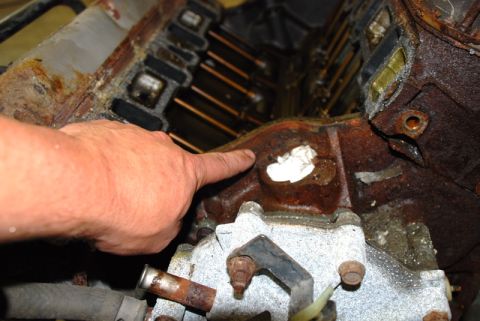 1996 Ford Bronco - Close-up of a corroded engine component, with a finger indicating a damaged area.