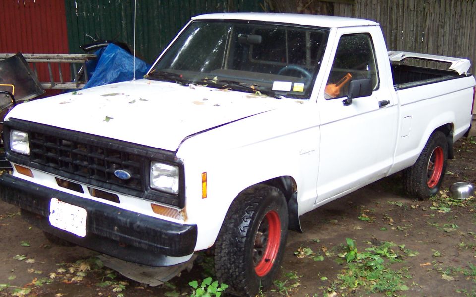 White Ford Ranger pickup truck with red rims parked outdoors