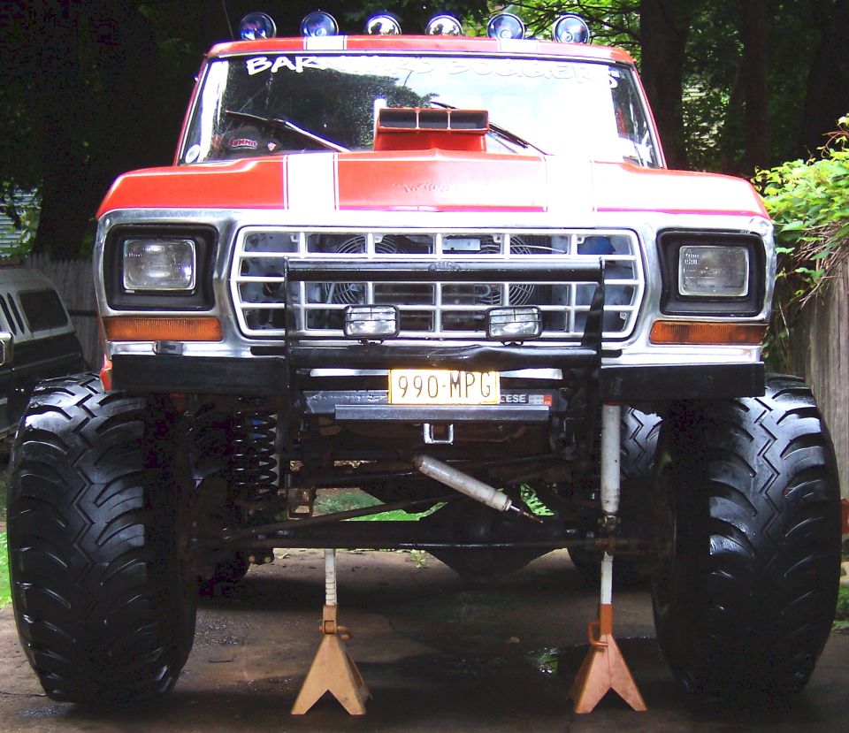 Red 1978 Ford Bronco with large tires, off-road lights, and a scoop on the hood