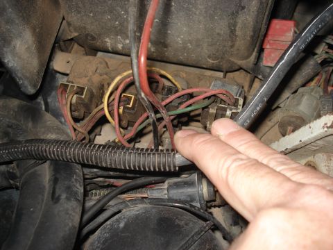 1986 Ford Bronco - Close-up of automotive fuse box and wiring harness. A hand is pointing to a connection.
