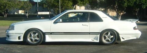 1987 Ford Thunderbird - Side profile of a white 1987 Ford Thunderbird coupe a custom body kit and alloy wheels.